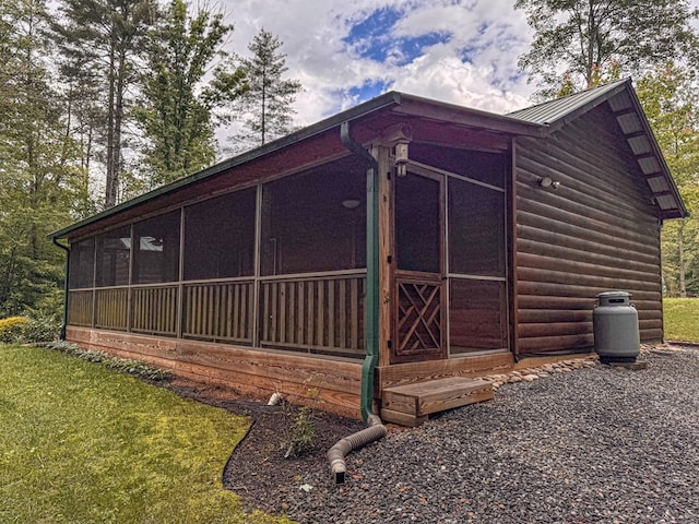 view of side of home featuring a sunroom, metal roof, faux log siding, and a yard