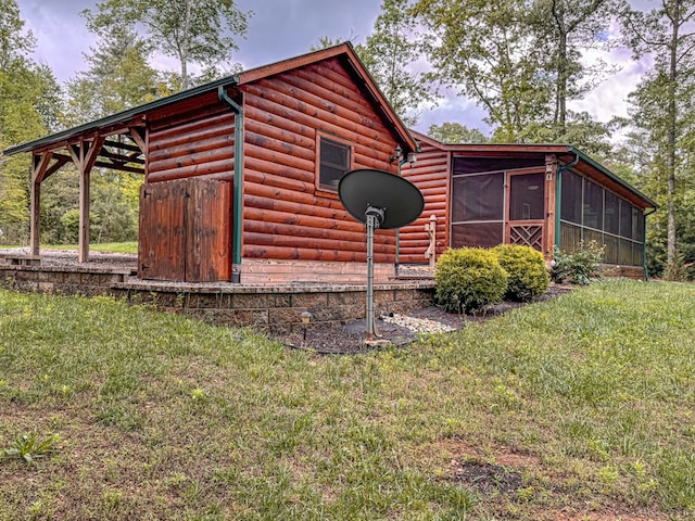 view of home's exterior featuring a sunroom, faux log siding, and a yard