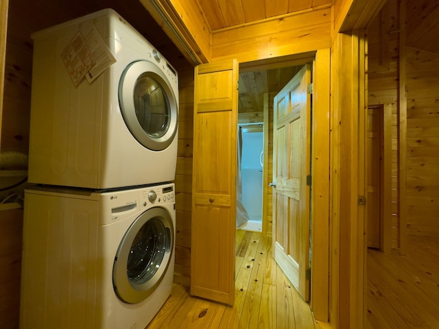 washroom featuring stacked washer and clothes dryer, wooden walls, light wood finished floors, and wood ceiling