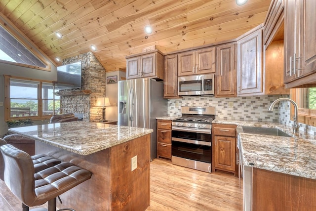 kitchen featuring a wealth of natural light, light stone countertops, sink, and appliances with stainless steel finishes