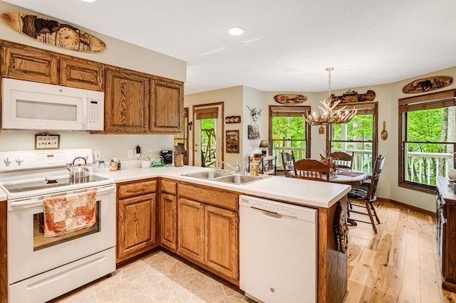 177 Lake Dr, Topton, NC 28781 - kitchen with white appliances, a sink, a peninsula, a chandelier, and brown cabinetry