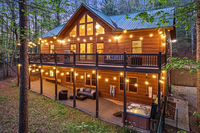 back of house featuring an outdoor living space, metal roof, a wooden deck, and a patio area