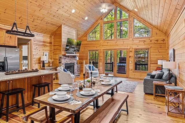 dining space featuring wood walls, a fireplace, and wooden ceiling