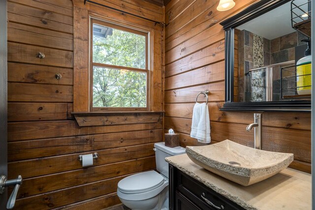 bathroom featuring vanity, a shower with shower door, toilet, and wooden walls