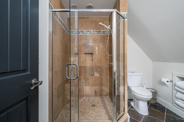 bathroom with lofted ceiling, toilet, and an enclosed shower