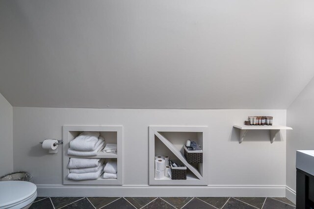 bathroom with vanity, toilet, tile patterned floors, and vaulted ceiling