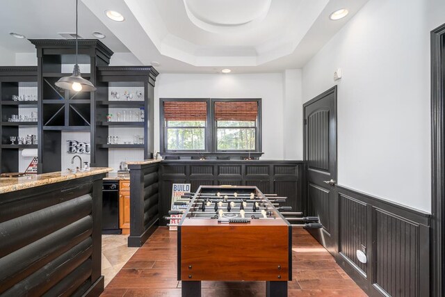 kitchen with hardwood / wood-style floors, light stone counters, and a tray ceiling