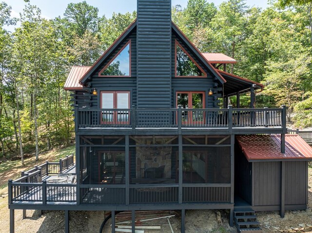 back of property with a wooden deck and a sunroom