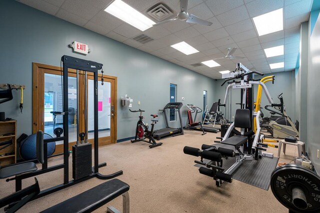 workout area with a paneled ceiling, carpet flooring, and ceiling fan