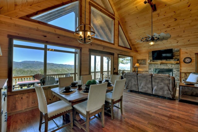 dining room with a stone fireplace, wood walls, a mountain view, and dark hardwood / wood-style floors