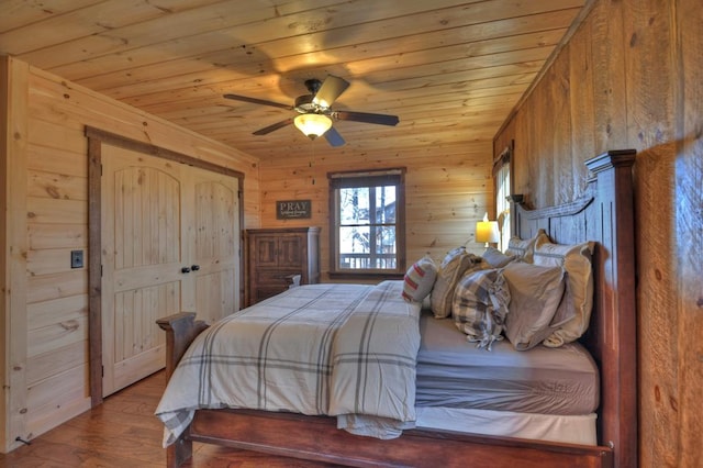 bedroom with a closet, hardwood / wood-style floors, ceiling fan, wood walls, and wood ceiling