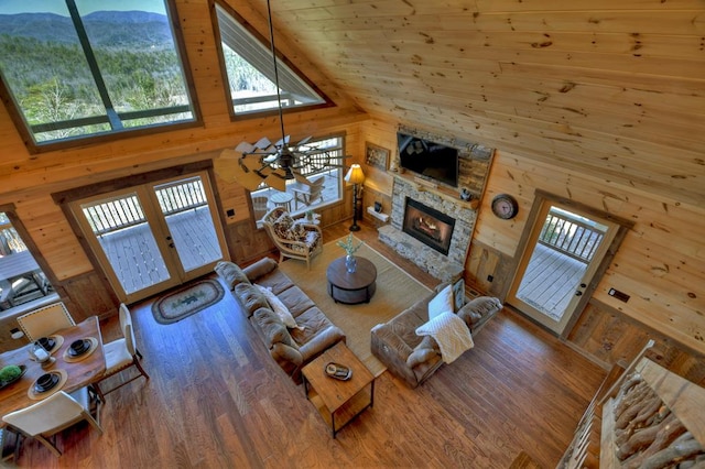 living room featuring hardwood / wood-style floors, a fireplace, high vaulted ceiling, a mountain view, and wood walls