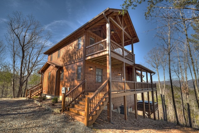 rear view of property featuring a balcony and central AC