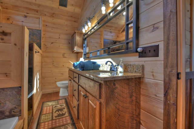 bathroom featuring hardwood / wood-style floors, lofted ceiling, wood walls, toilet, and vanity