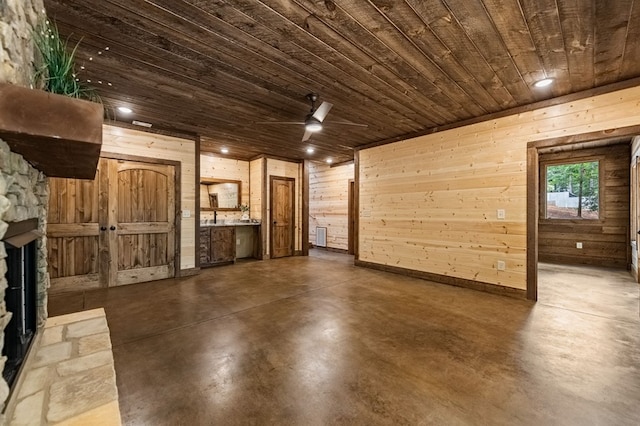 unfurnished living room with wooden walls, ceiling fan, wooden ceiling, and a stone fireplace