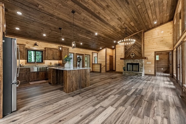 kitchen featuring dark hardwood / wood-style floors, a center island, hanging light fixtures, and stainless steel refrigerator