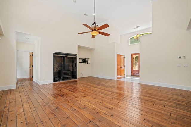 705 Brown Deer Dr, Talking Rock, GA 30175 - unfurnished living room featuring a wood stove, wood-type flooring, ceiling fan, ornamental molding, and a towering ceiling