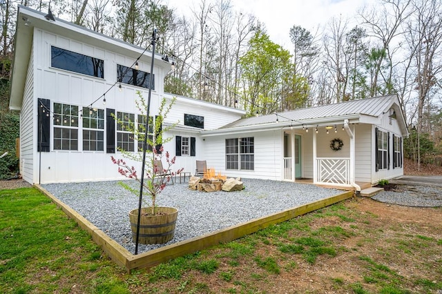 back of property with a fire pit, metal roof, board and batten siding, and a sunroom