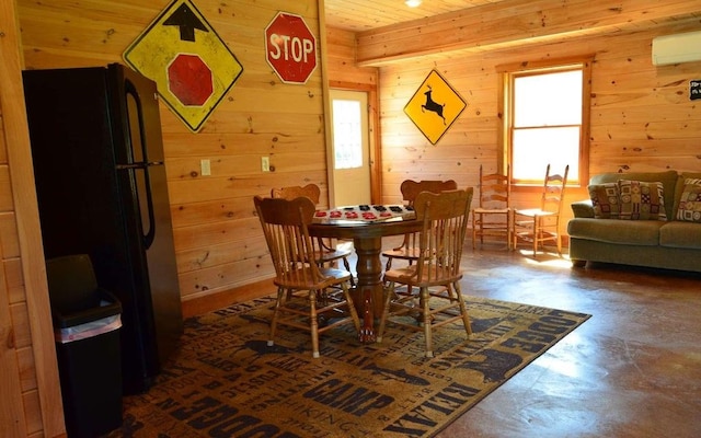 dining area with plenty of natural light, wooden walls, and concrete floors