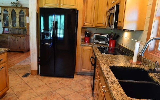 kitchen featuring sink, black appliances, and light stone counters