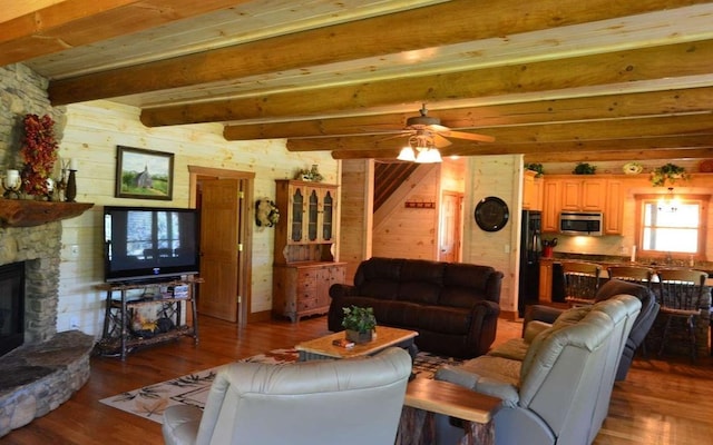 living room featuring hardwood / wood-style flooring, a fireplace, wooden walls, and beamed ceiling