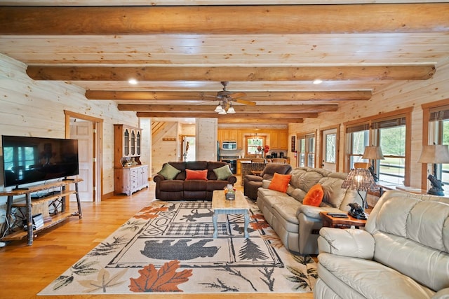 living room with light hardwood / wood-style floors, wooden walls, ceiling fan, and beam ceiling