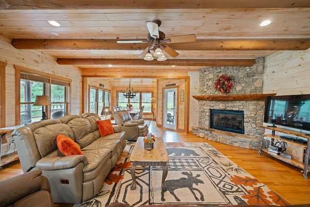 living room with a fireplace, plenty of natural light, beamed ceiling, and light hardwood / wood-style flooring