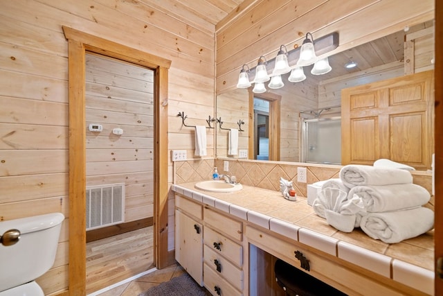 bathroom featuring wood walls, tile patterned flooring, vanity, and a shower with door