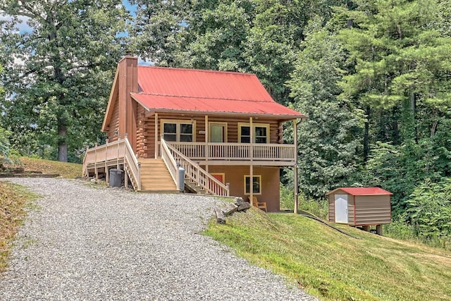 log cabin featuring a front yard, a deck, and a storage shed