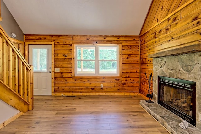 unfurnished living room with light hardwood / wood-style floors, a stone fireplace, plenty of natural light, and lofted ceiling