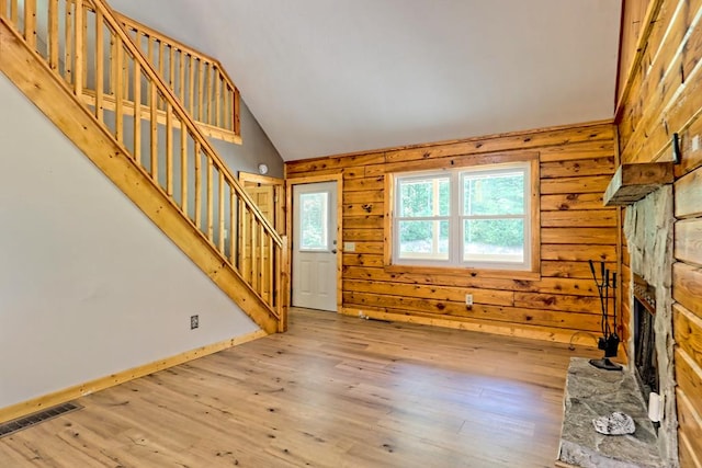 unfurnished living room with a stone fireplace, hardwood / wood-style floors, and lofted ceiling