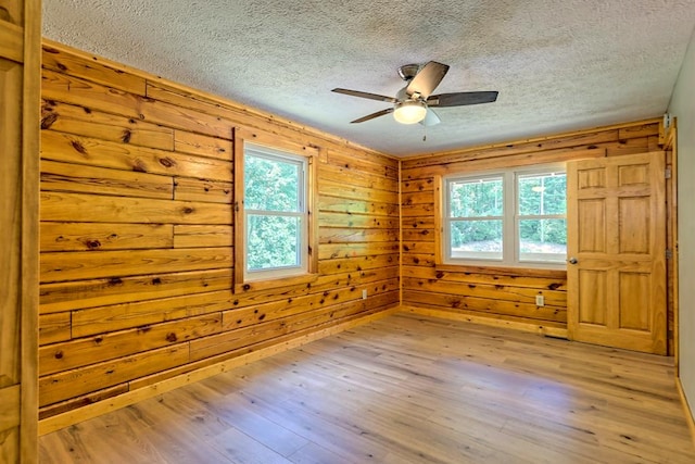 interior space featuring ceiling fan, wood walls, and light hardwood / wood-style floors