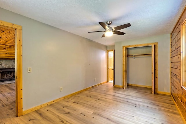 unfurnished bedroom featuring a textured ceiling, a closet, light hardwood / wood-style flooring, and ceiling fan