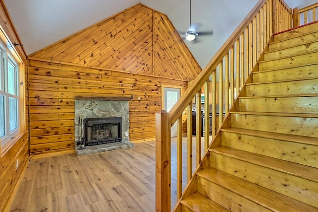 stairway with a fireplace, wood-type flooring, a healthy amount of sunlight, and wood walls