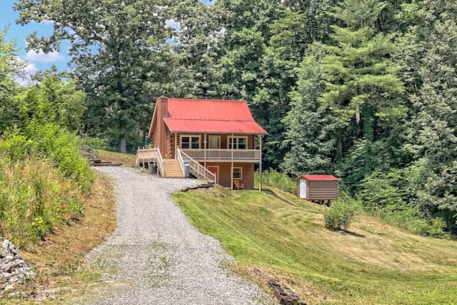 view of front of property with a shed, a deck, and a front yard