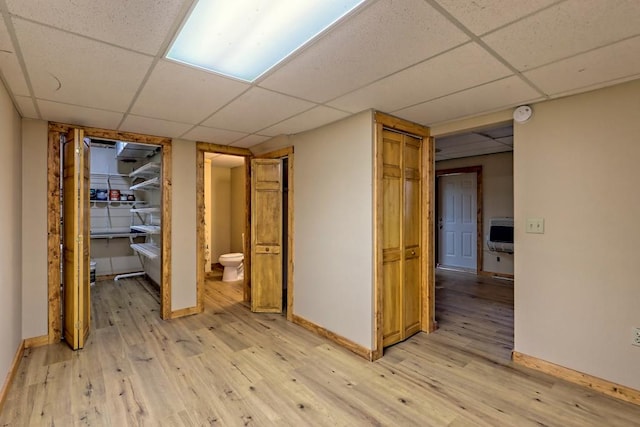 interior space featuring a paneled ceiling, light hardwood / wood-style floors, and heating unit