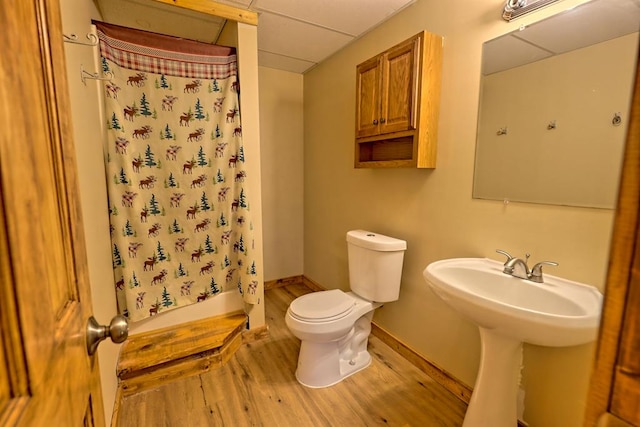 bathroom featuring a shower with shower curtain, a drop ceiling, toilet, and hardwood / wood-style flooring