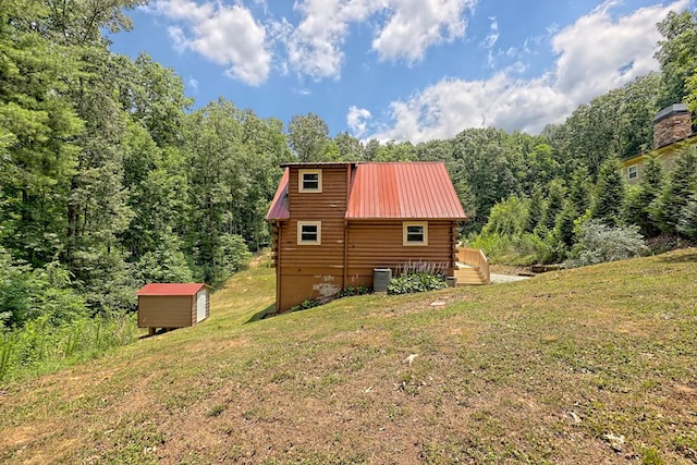 exterior space featuring a lawn, a wooden deck, cooling unit, and a shed