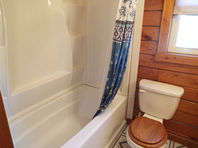 bathroom featuring shower / bathtub combination with curtain, toilet, and wooden walls