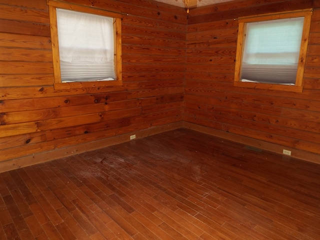 empty room featuring wooden walls and wood finished floors