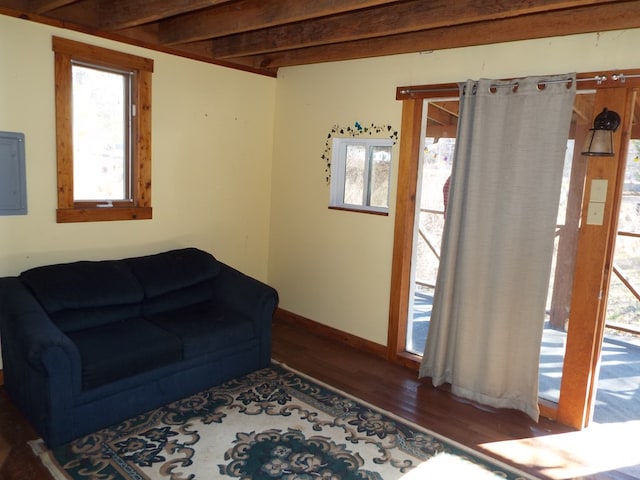 living room with beamed ceiling, wood finished floors, electric panel, and baseboards