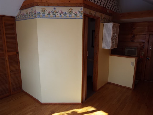 hallway featuring a wall mounted air conditioner, wood finished floors, and baseboards