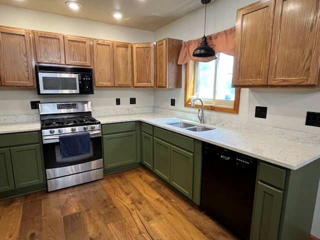 kitchen featuring green cabinetry, dark wood-type flooring, a sink, and appliances with stainless steel finishes