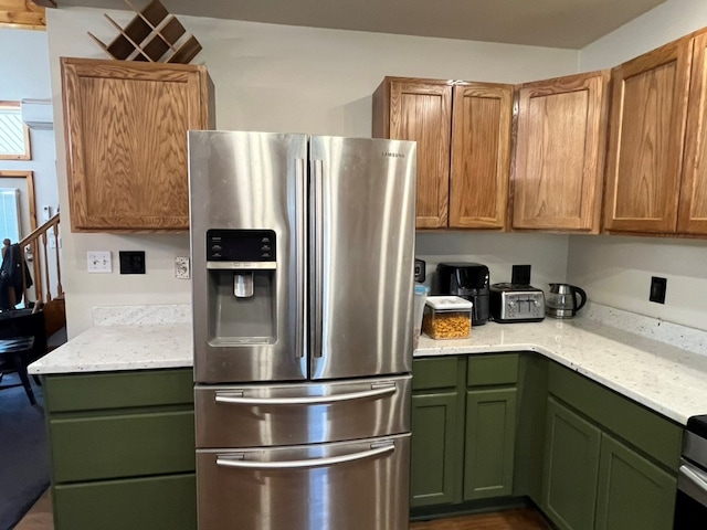 kitchen with green cabinets, stainless steel fridge with ice dispenser, and light stone countertops