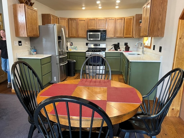 kitchen featuring green cabinets, recessed lighting, light countertops, stainless steel appliances, and a sink