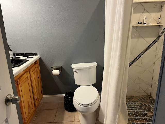 bathroom featuring baseboards, a tile shower, toilet, vanity, and tile patterned flooring