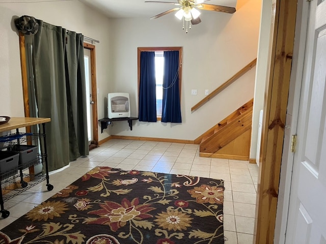 entrance foyer featuring ceiling fan, stairway, light tile patterned flooring, baseboards, and heating unit