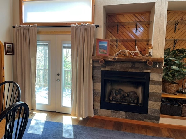 doorway with french doors, a fireplace, wood finished floors, and a healthy amount of sunlight