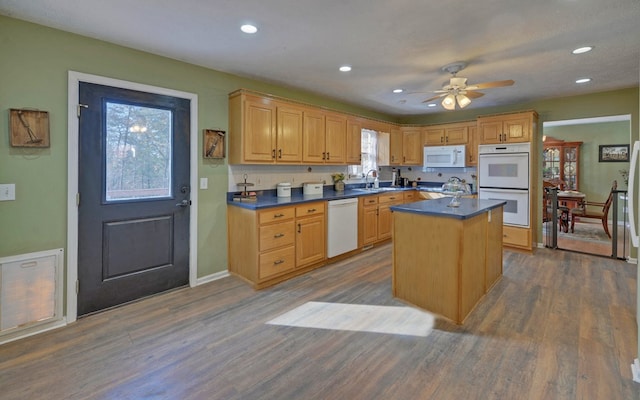 kitchen featuring dark hardwood / wood-style flooring, a kitchen island, sink, and white appliances