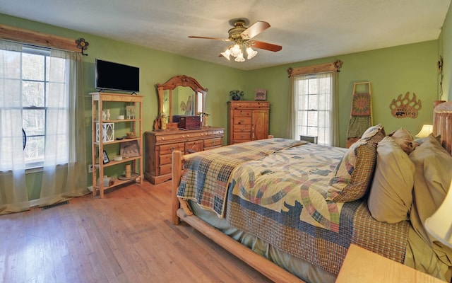 bedroom with ceiling fan, a textured ceiling, and light wood-type flooring